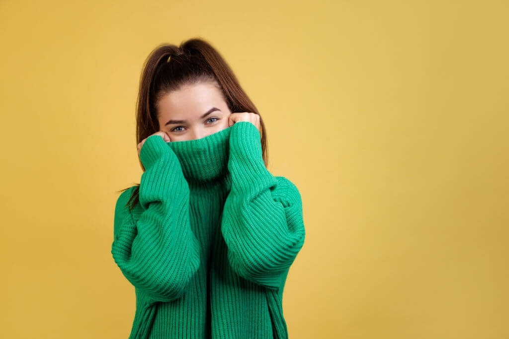 Girl in green sweater covering her face